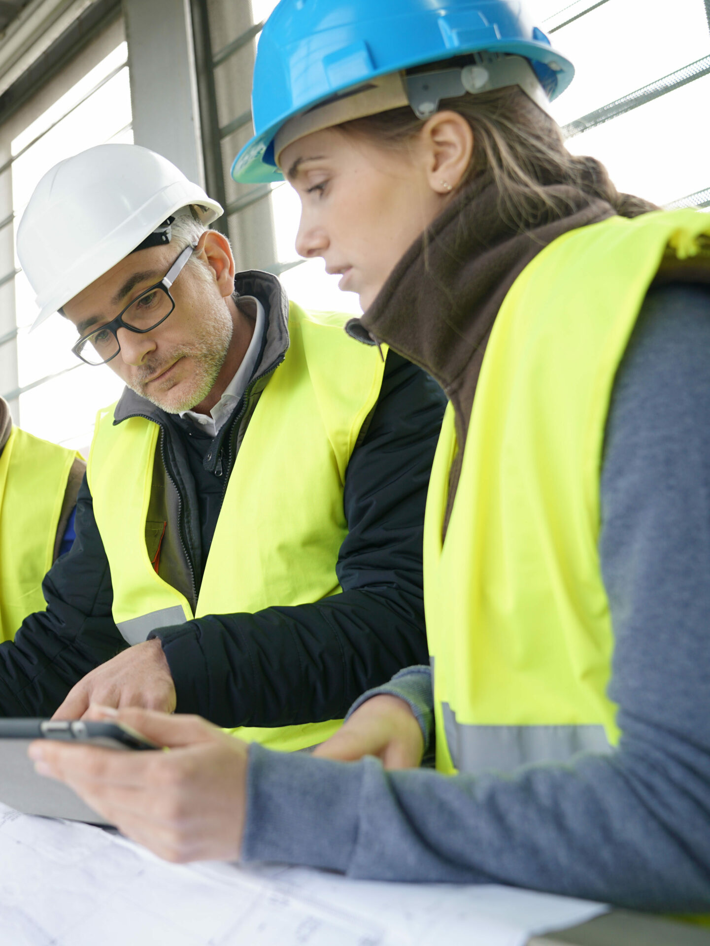 Deux personnes discutent sur un chantier autour de plans de travaux